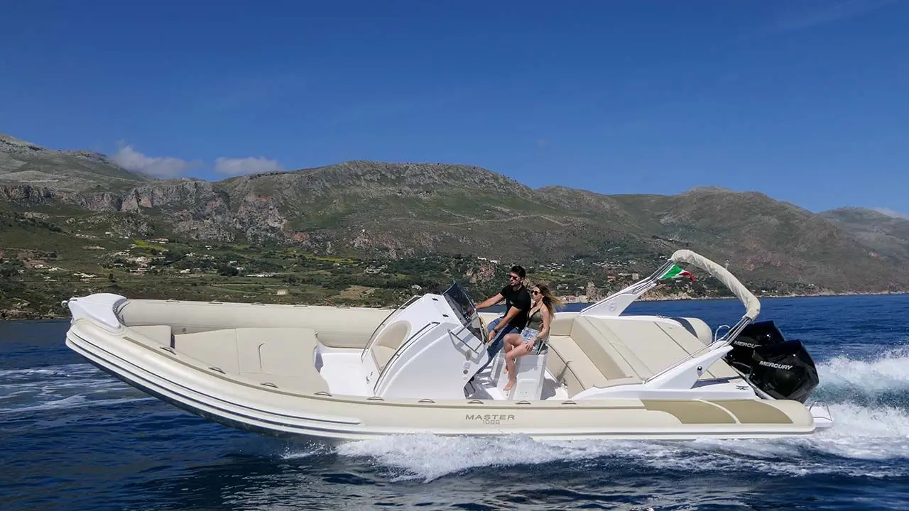 Master 1000 — Bateau semi-rigide naviguant devant un littoral montagneux.