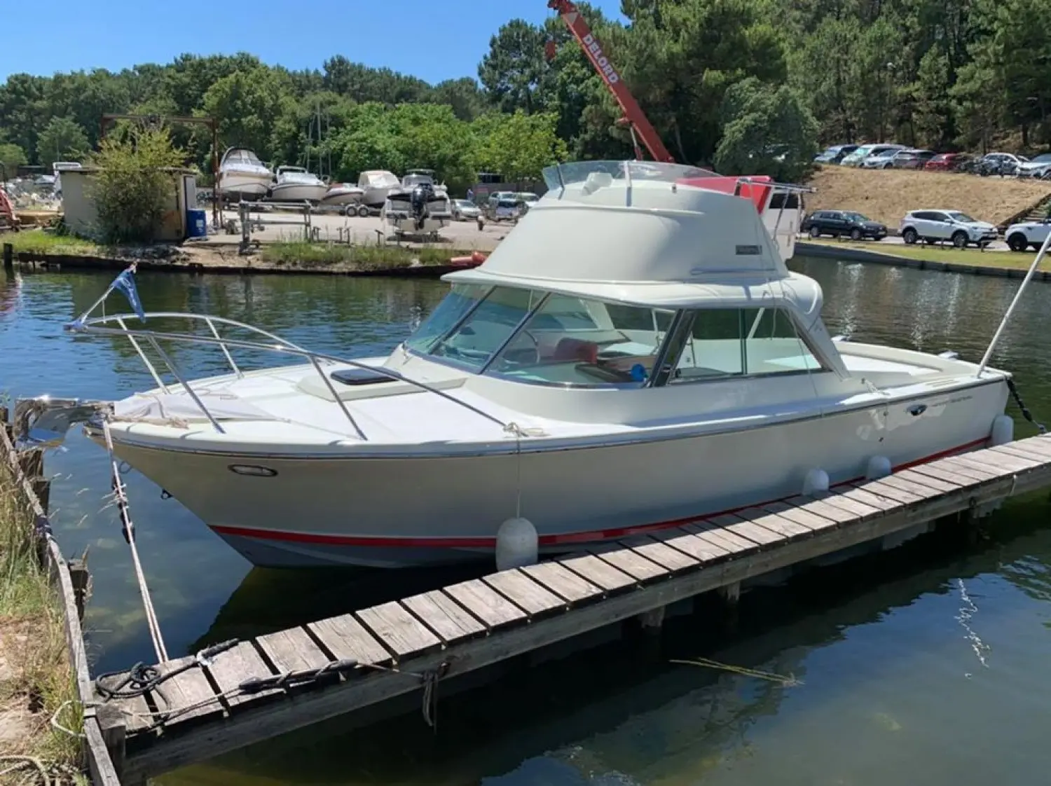 Riva Bertram 25 Sport Fisherman — Bateau à moteur blanc amarré à un ponton, vu de trois quarts.