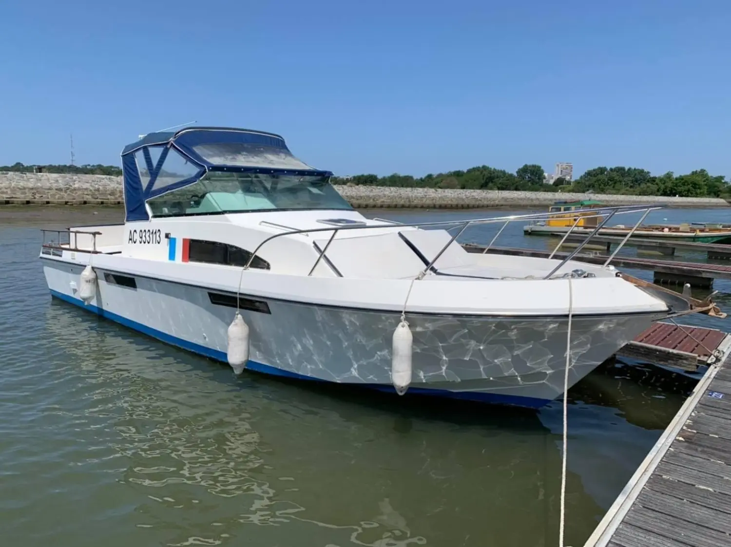 Guy Couach Pyla 1000 — Bateau à moteur blanc amarré dans un port, vu de trois quarts avant.