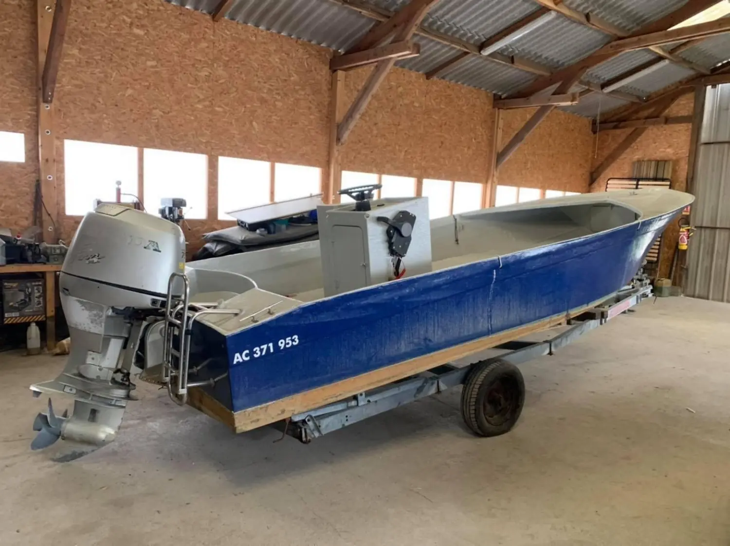 Trident Marine Plate — Bateau à moteur bleu et blanc photographié sur sa remorque dans un hangar.