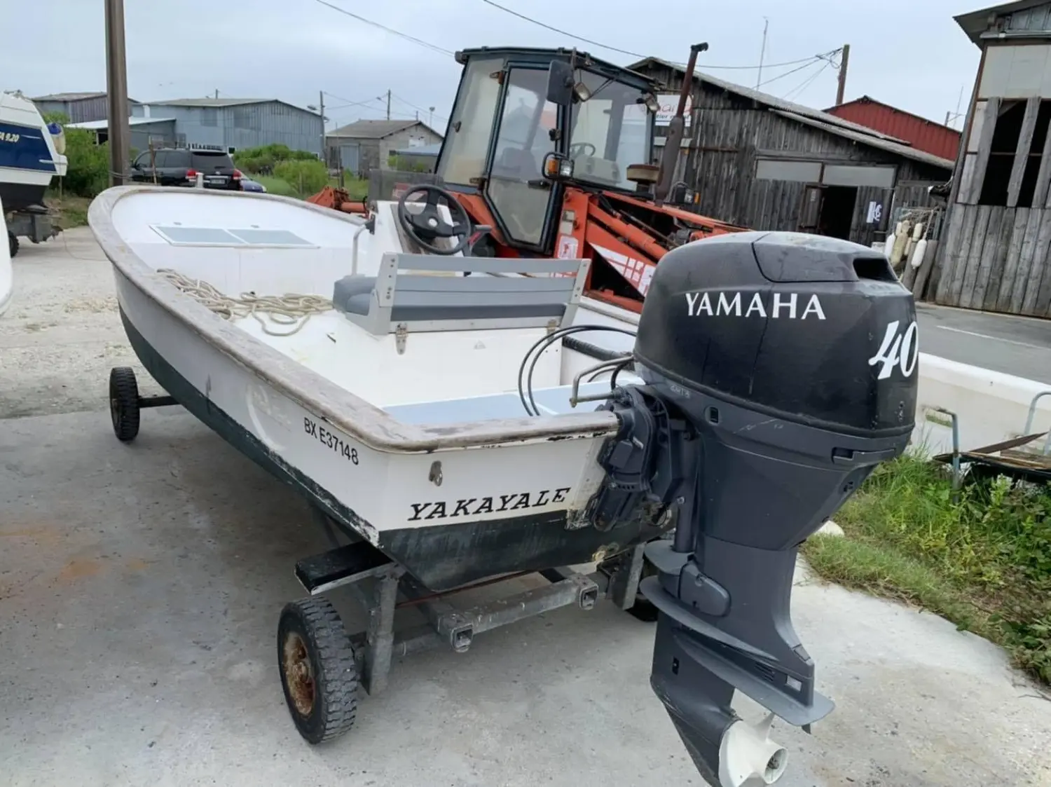 Plate Polyester — Bateau à moteur hors-bord sur remorque, photographié dans une zone portuaire.