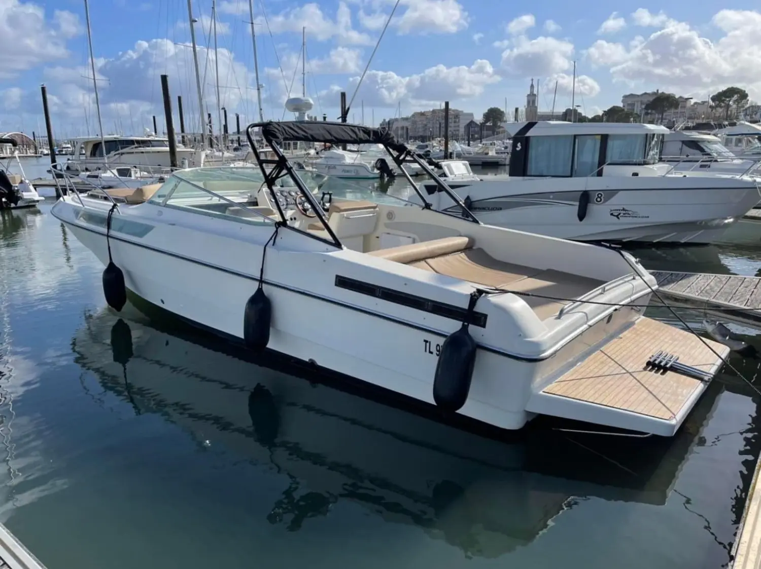 Guy Couach 950 — Bateau à moteur blanc vu de trois quarts arrière dans une marina.