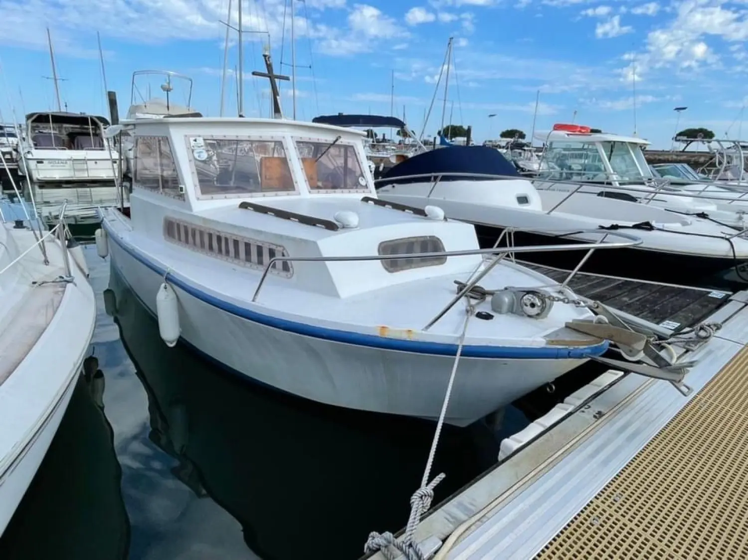 Guy Couach 660 — Bateau à moteur blanc amarré dans un port de plaisance, vu de trois quarts avant.