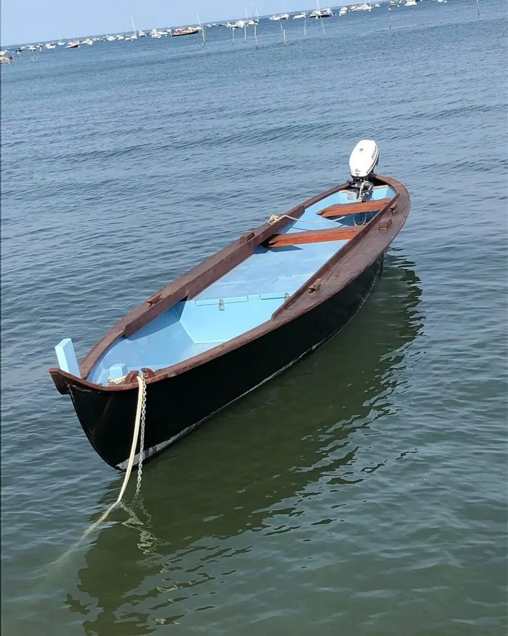 Windrider Pinassotte — Bateau à moteur ouvert noir et bleu amarré dans une baie, vu de trois quarts.