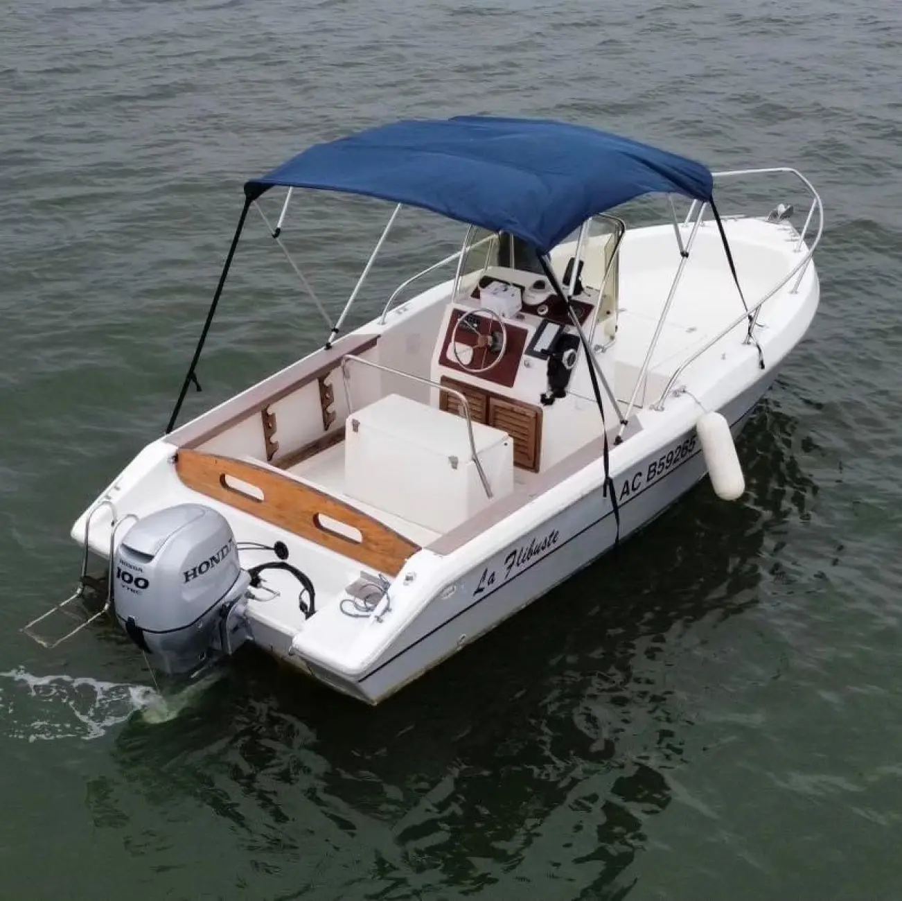 Capelli Cap 19 Open — Bateau à moteur blanc vu de trois quarts arrière, avec taud bleu et moteur hors-bord.