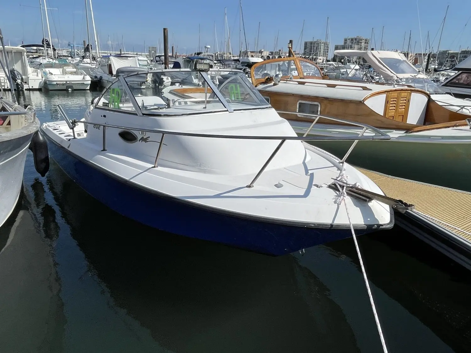 Sunbird Fishing 202 — Bateau à moteur blanc et bleu amarré dans un port de plaisance.