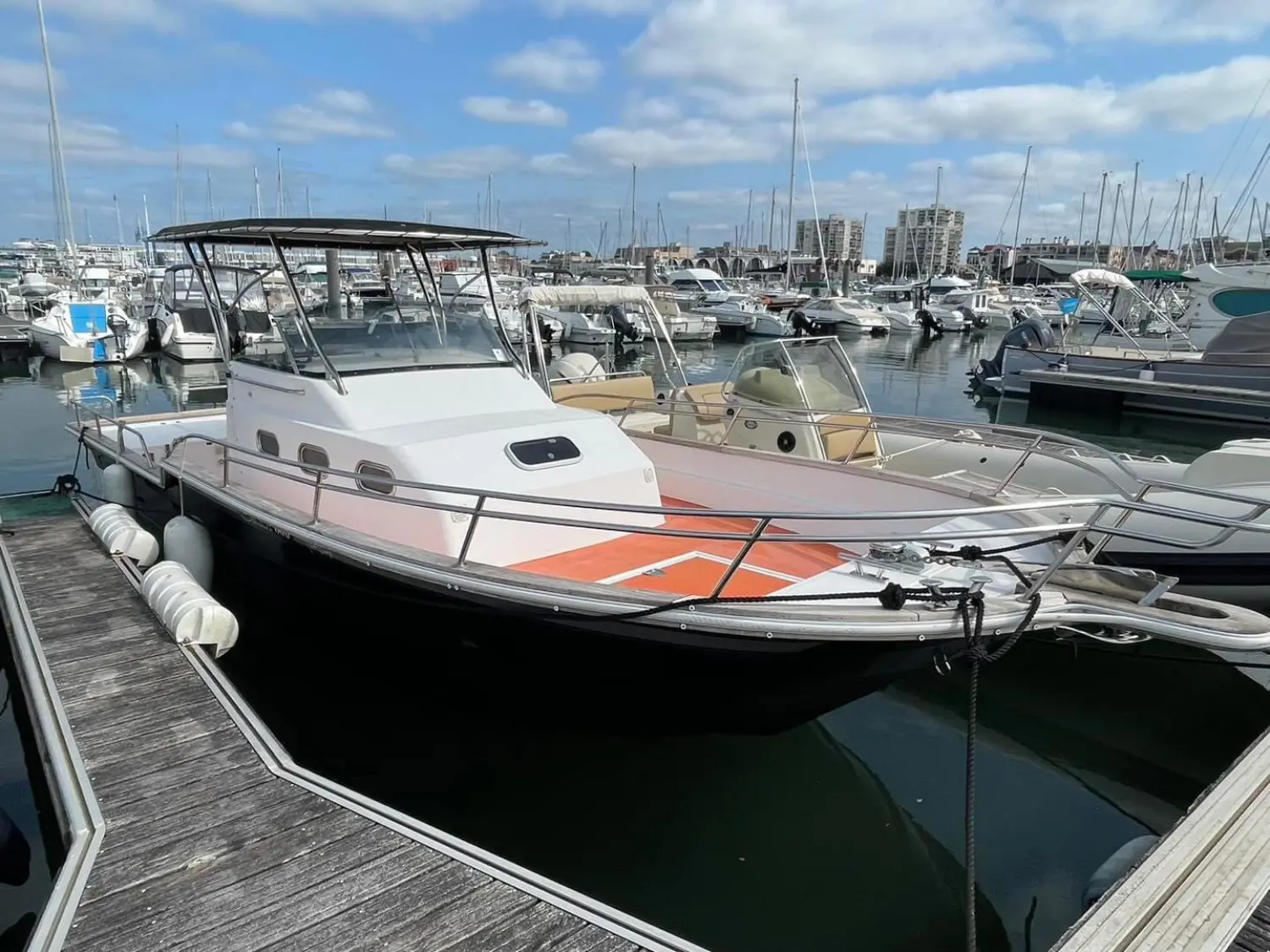 Orka 800 — Bateau à moteur blanc et noir amarré dans une marina, vu de trois quarts avant.
