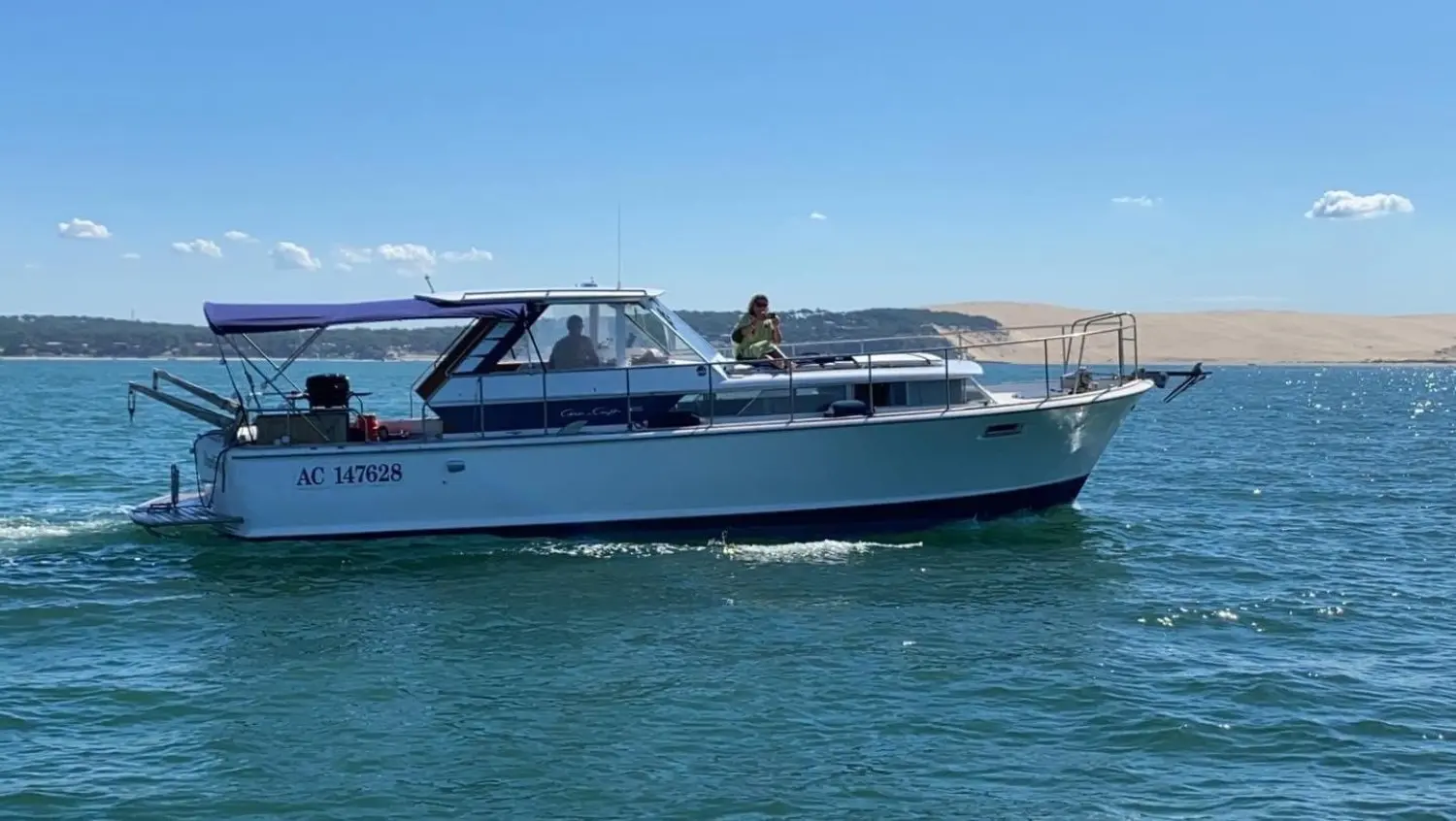 Chris Craft Commander 38 — Bateau à moteur blanc naviguant sur une baie, vu de profil par temps ensoleillé.