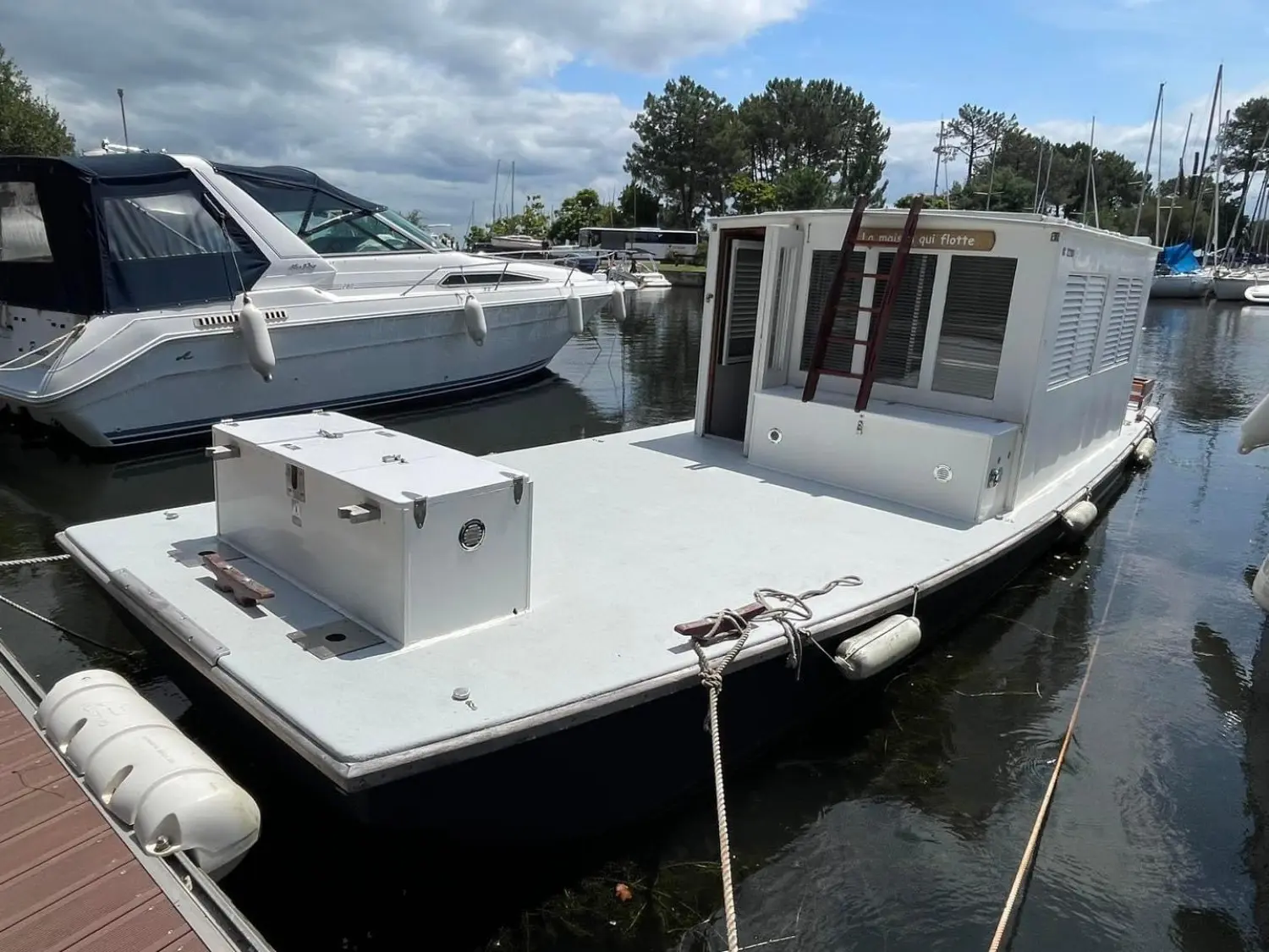 Carrere Bac De Plaisance — Bateau habitable amarré dans un port, avec cabine blanche et large pont avant.