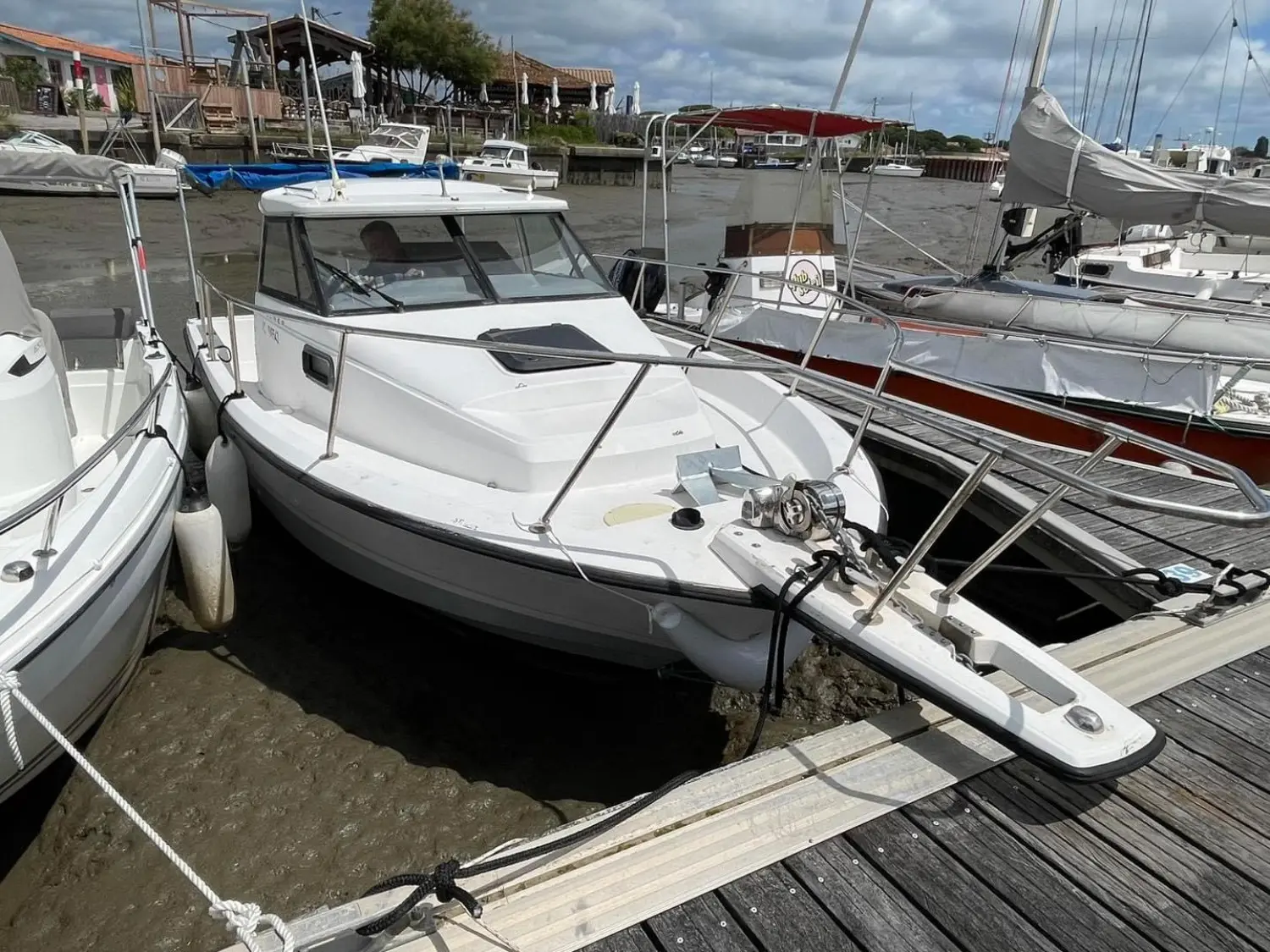 Bayliner Trophy 2352 — Bateau à cabine blanc amarré dans un port à marée basse.