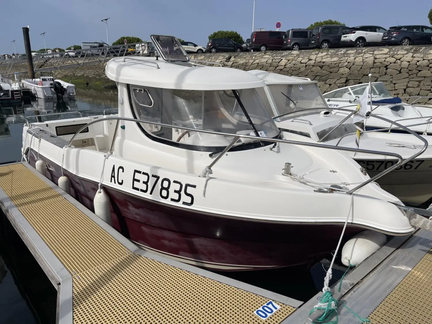 Arvor 215 — Bateau à cabine blanche et coque bordeaux amarré dans un port.