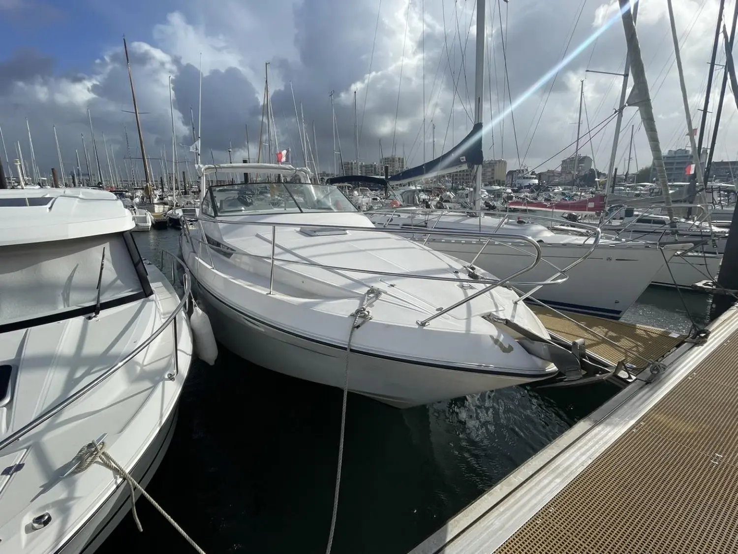 Yachting France Arcoa 975 — Bateau à moteur blanc amarré dans une marina, entouré de voiliers.