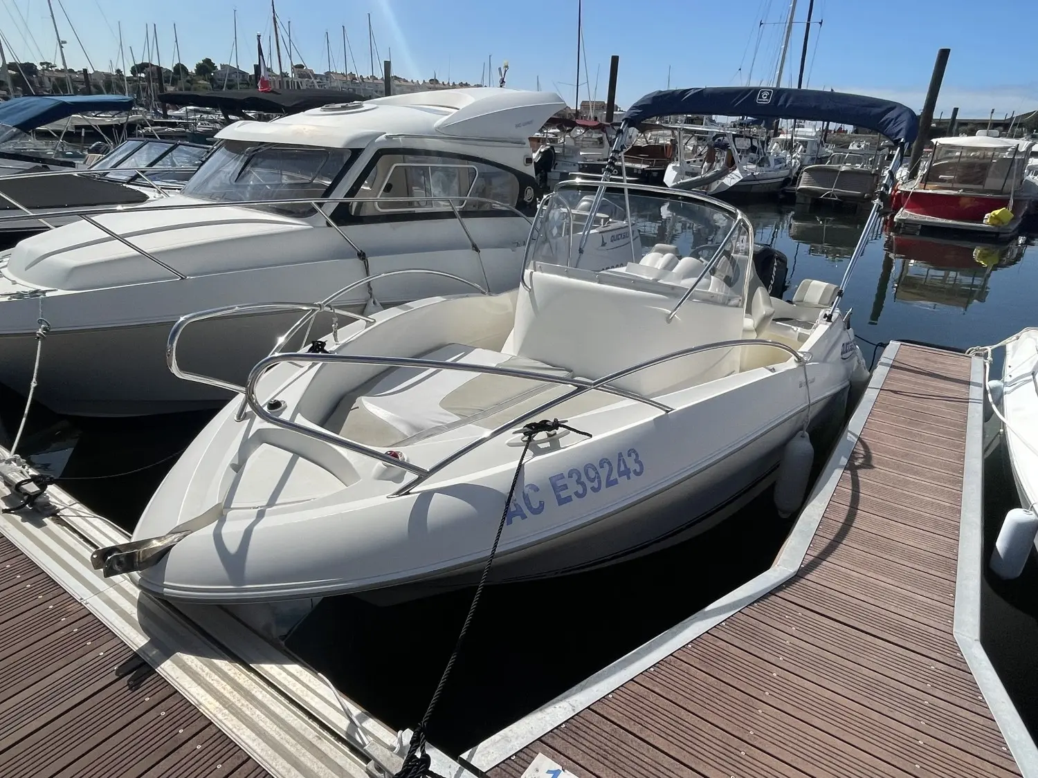 Quicksilver 555 Open — Bateau à moteur blanc vu de trois quarts dans un port de plaisance.