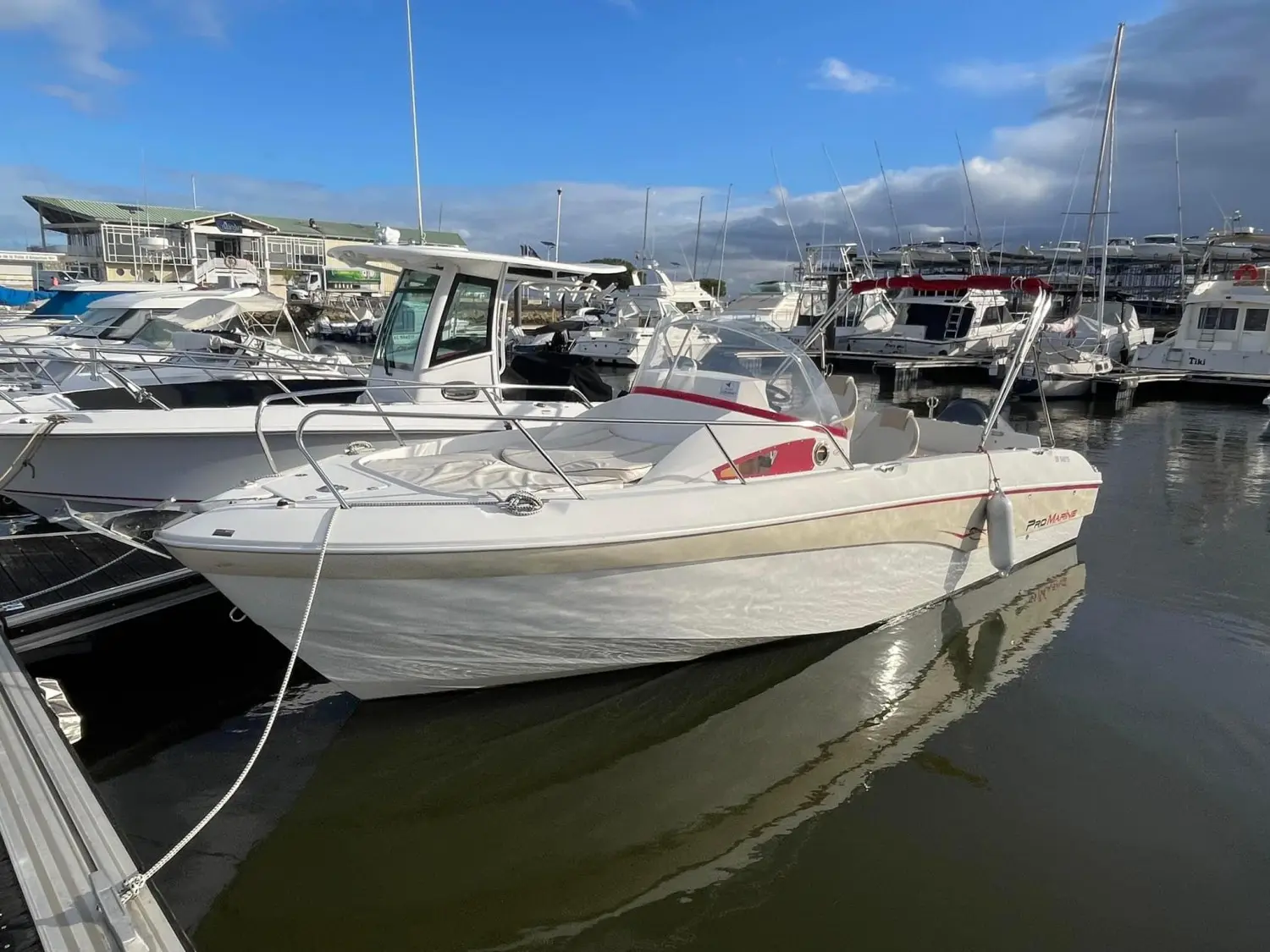 Pro Marine Belone 740 — Bateau à moteur blanc amarré dans une marina, vu de trois quarts avant.
