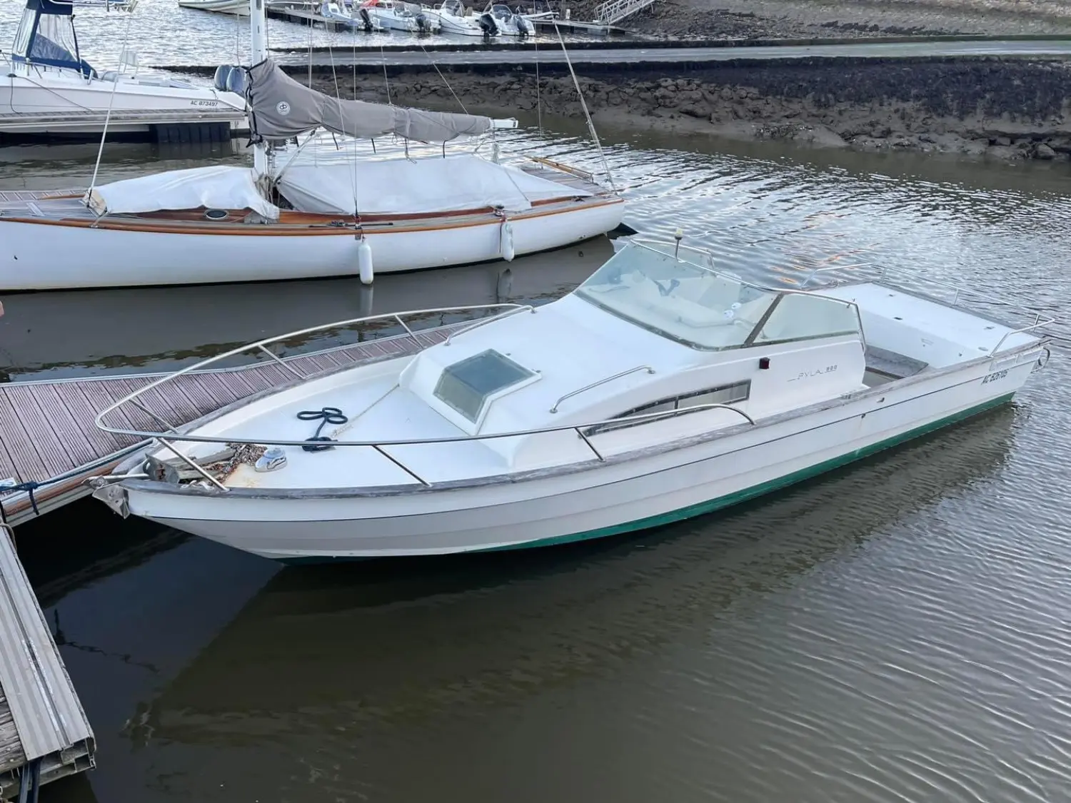 Guy Couach Pyla 800 — Bateau à moteur blanc amarré dans un port, vu de trois quarts avant.