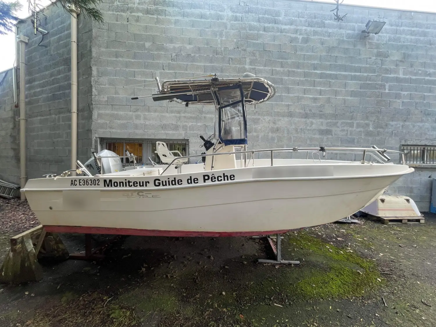 Arc Eyre 585 Open — Bateau à moteur blanc présenté à terre, vu de profil, avec console centrale et T-top.