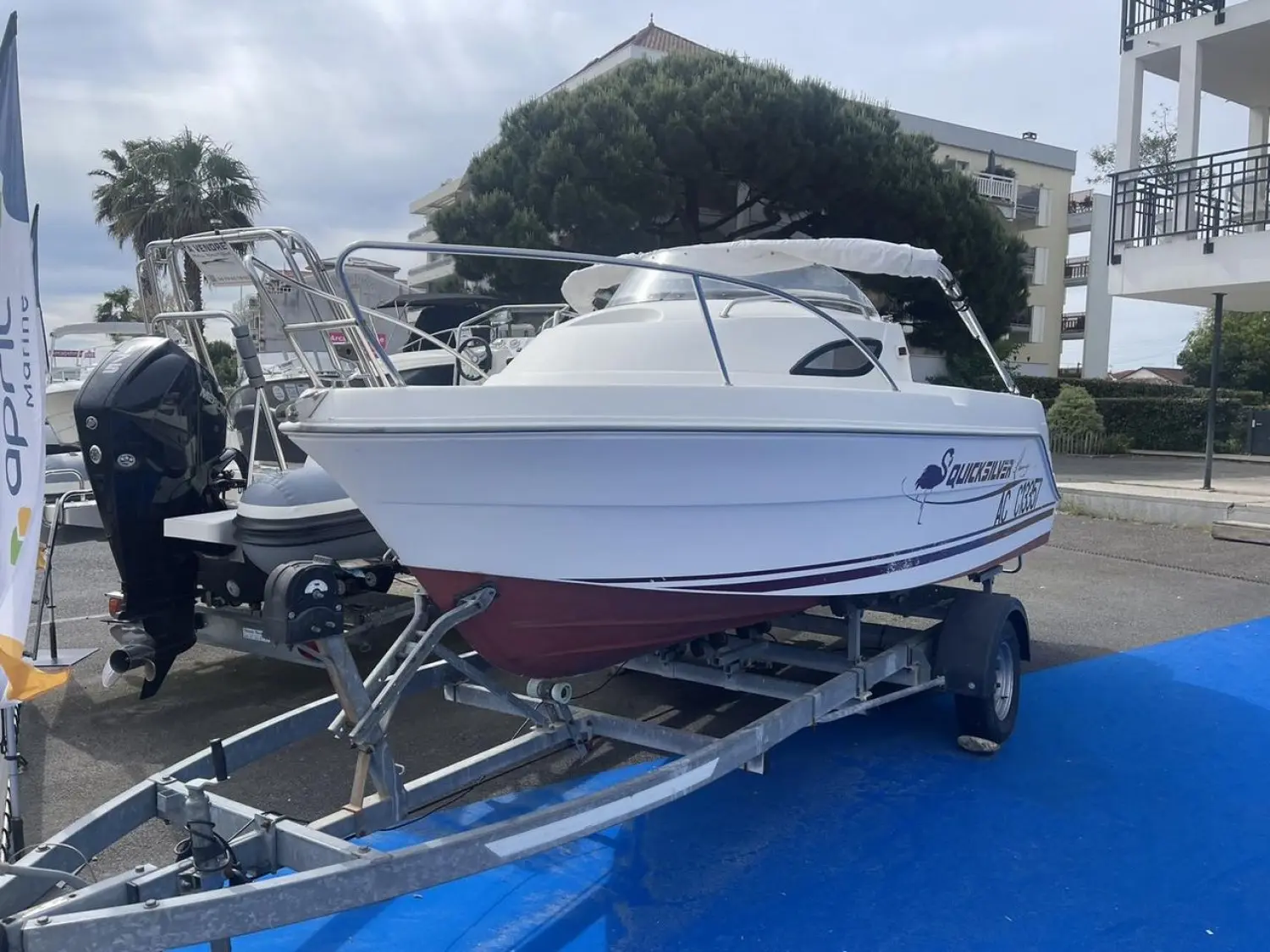 Quicksilver 520 Flamingo — Bateau à moteur blanc et rouge présenté sur remorque, vu de trois quarts arrière.