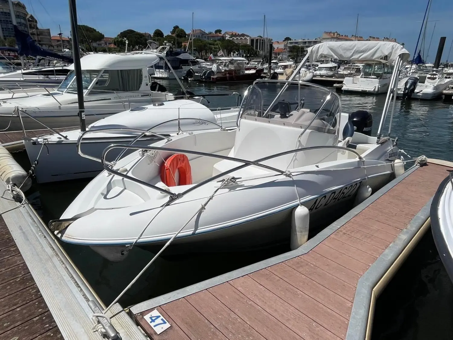 Quicksilver 555 Open — Bateau à moteur blanc amarré dans un port, vu de trois quarts avant.