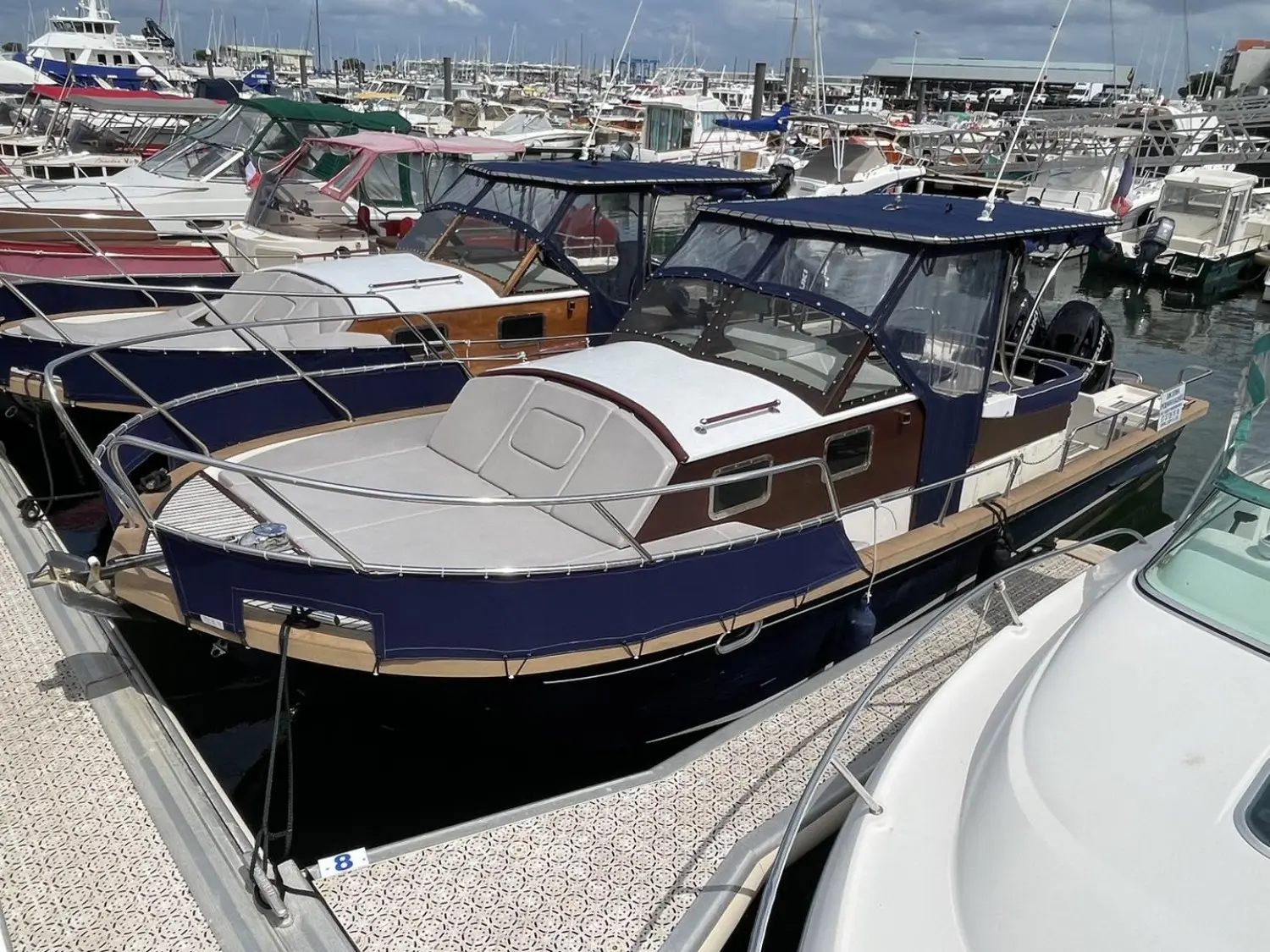 Beacher 840 — Bateau à cabine bleu et blanc amarré dans un port de plaisance.