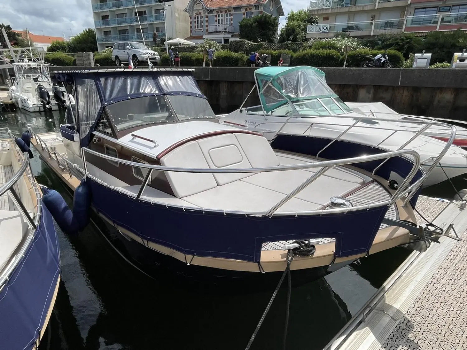 Beacher 840 — Bateau à coque bleue et pont blanc amarré dans une marina.