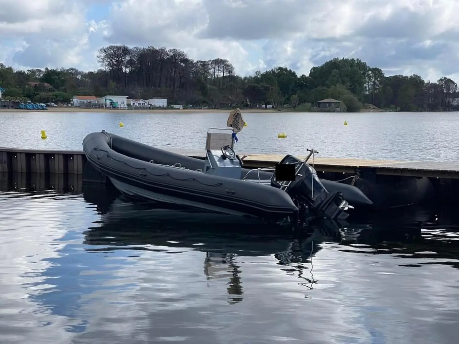 Narwhal SP 750 — Bateau pneumatique noir amarré à un ponton sur un lac.