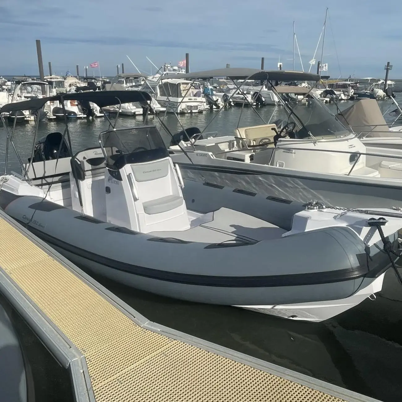 Ranieri Cayman 23 S — Semi-rigide blanc et gris amarré dans une marina, vu de trois quarts.