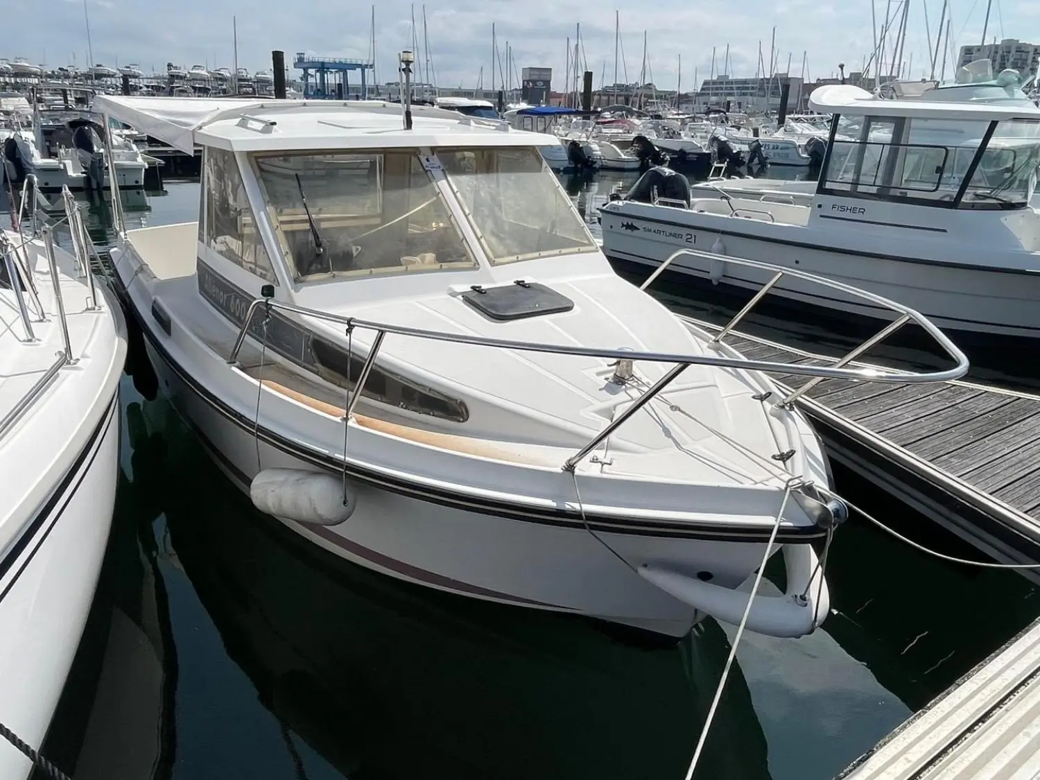 Ocqueteau Alienor 600 — Bateau à cabine amarré dans un port de plaisance, vu de trois quarts avant.