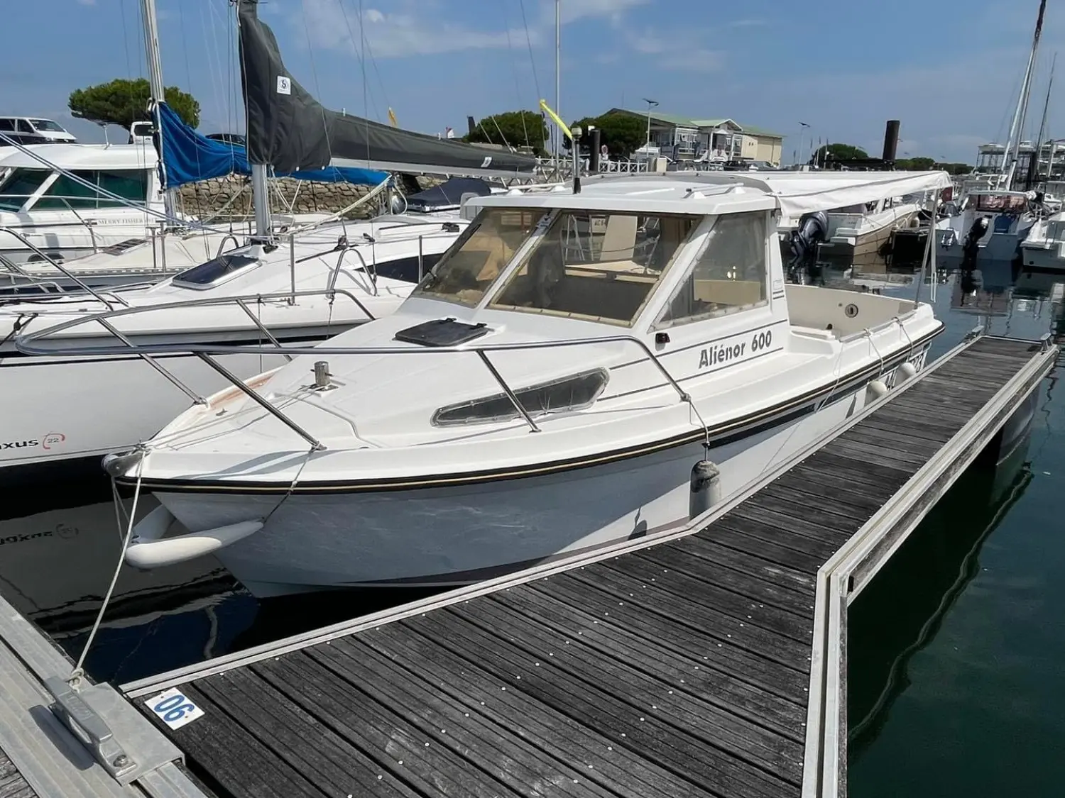 Ocqueteau Alienor 600 — Bateau à moteur blanc amarré dans un port, vu de trois quarts avant.