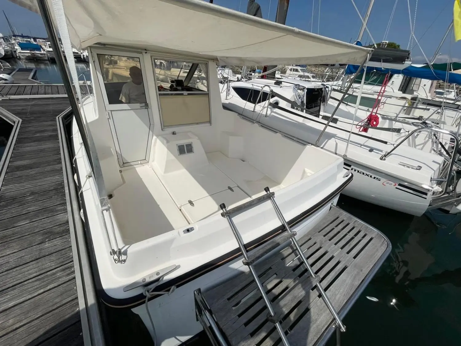 Ocqueteau Alienor 600 — Vue arrière du cockpit et de la cabine d’un bateau amarré au ponton.