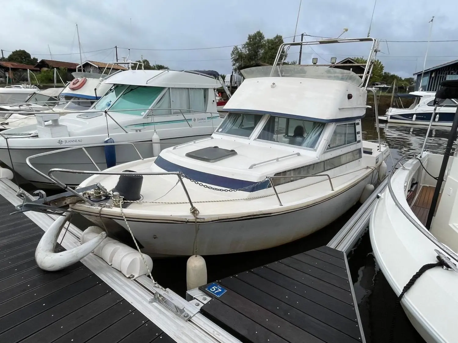 Guy Couach 730 — Bateau à moteur blanc amarré dans un port, vu de trois quarts avant.