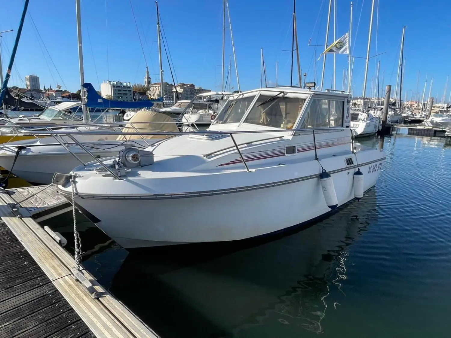 Beneteau Antares 730 — Bateau à moteur blanc amarré dans une marina, vu de trois quarts avant.