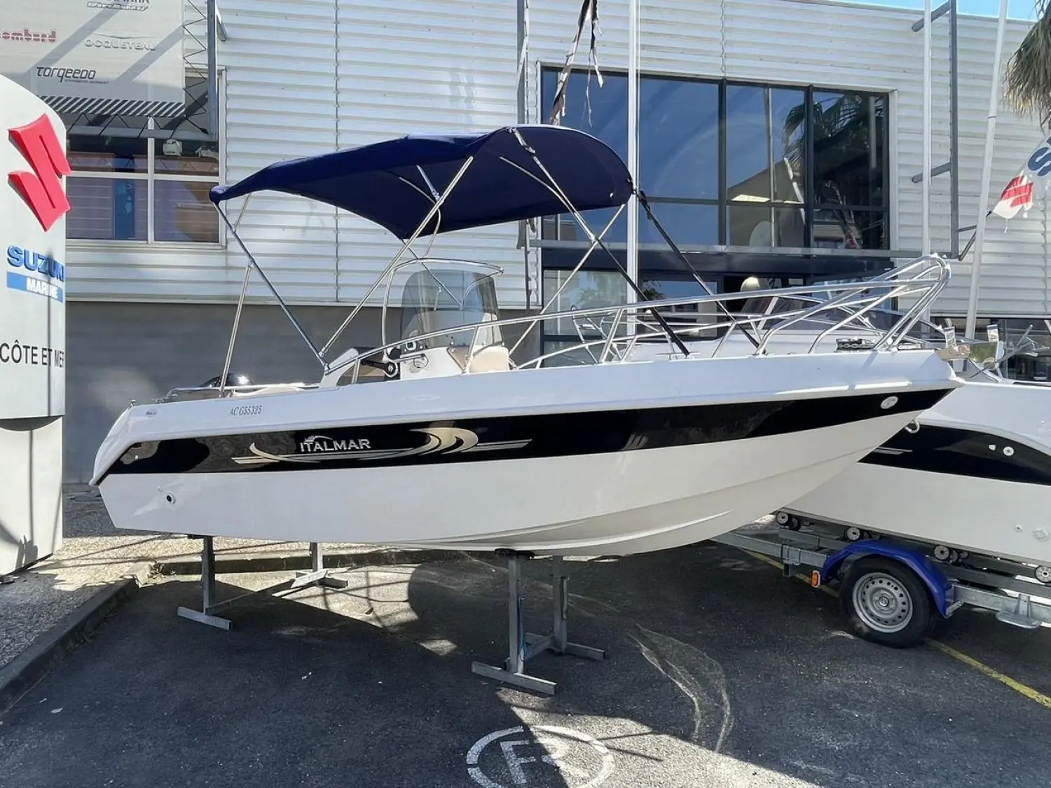 Italmar Open 19 — Bateau à coque blanche et bande noire, photographié sur remorque devant un bâtiment.