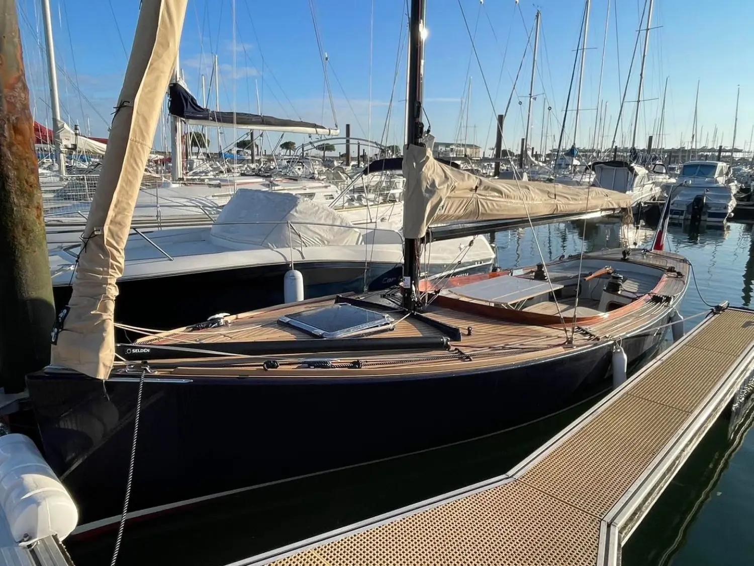 Rosewest Cape Cod 896 — Voilier vu de trois quarts dans un port, avec voiles et capote repliées.