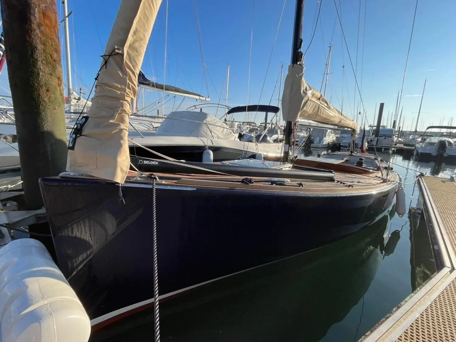 Rosewest Cape Cod 896 — Voilier amarré dans une marina, vu de l’avant entre des pontons.
