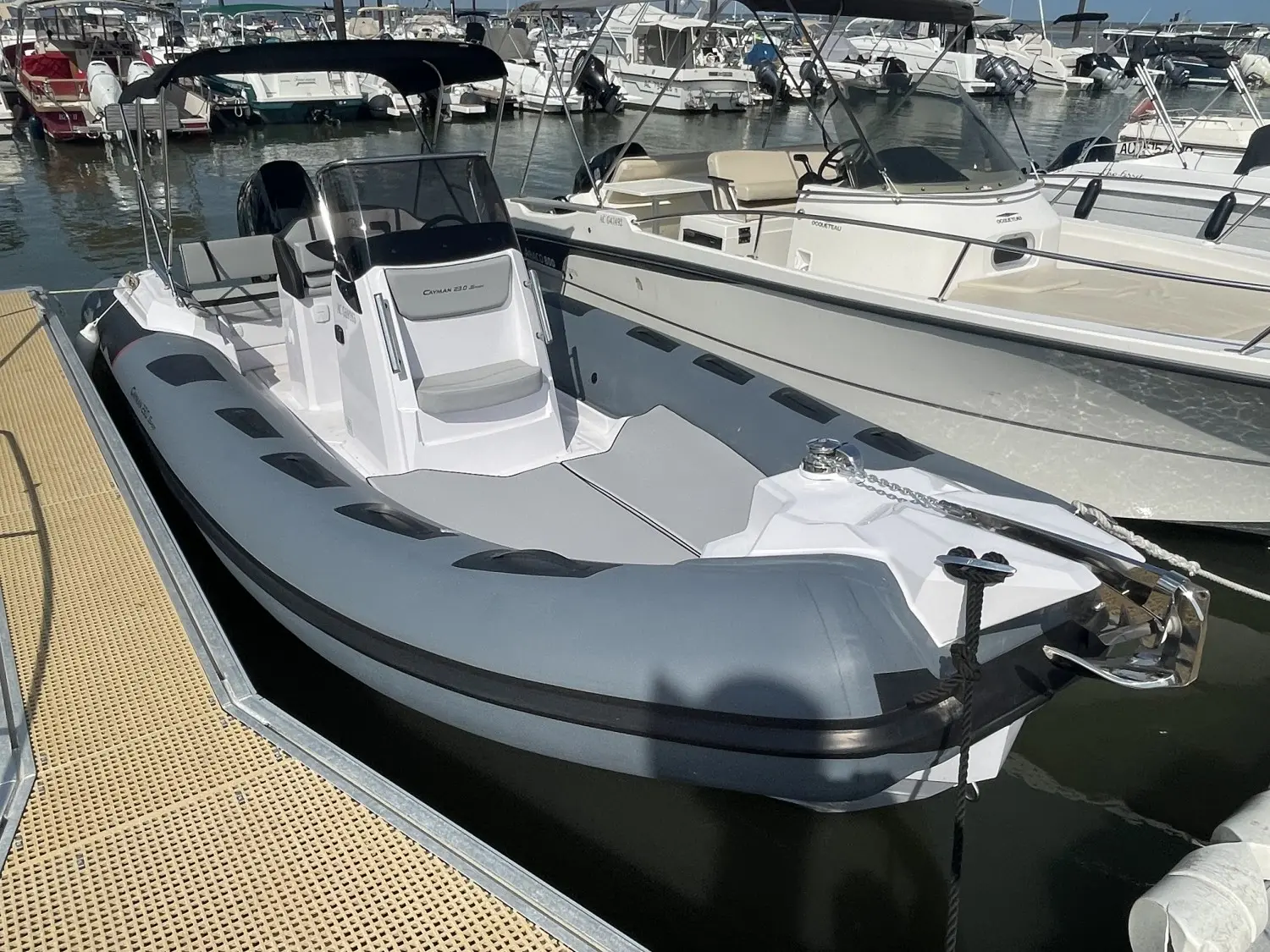 Ranieri Cayman 23 S — Semi-rigide blanc vu de trois quarts avant dans un port de plaisance.