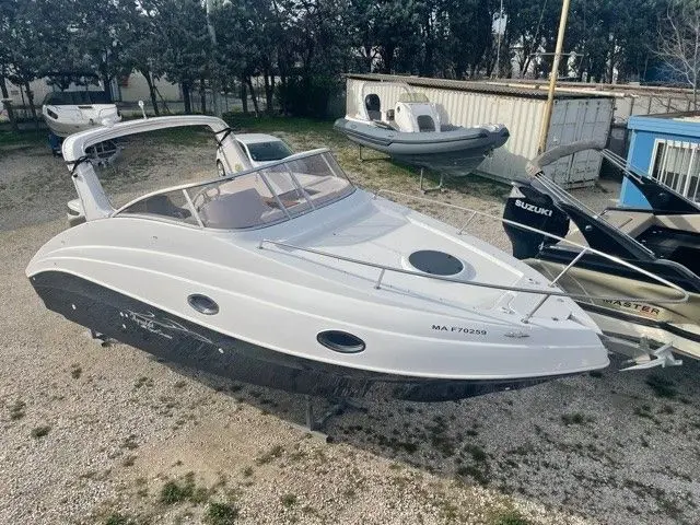Aquabat sport cruiser — Bateau à moteur blanc vu de trois quarts sur remorque, dans une cour extérieure.