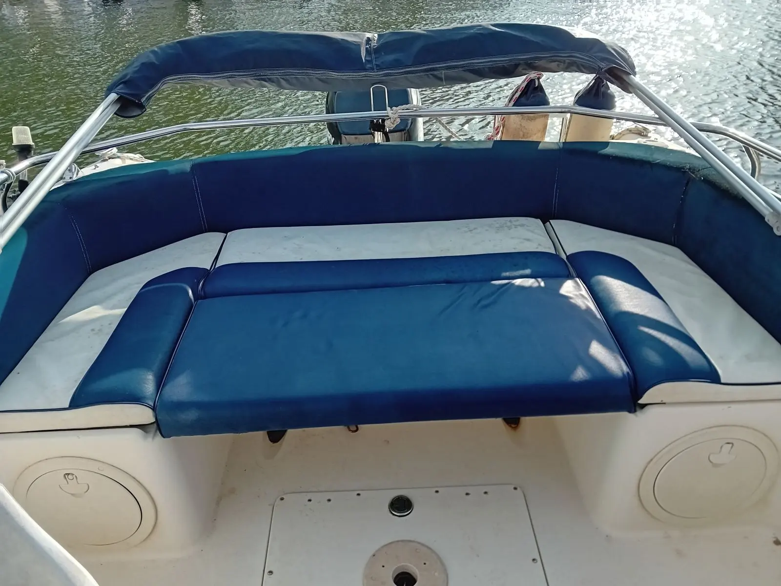 Drago Sorocos 640 — Cockpit extérieur avec banquette rembourrée bleue et taud sur l’eau.