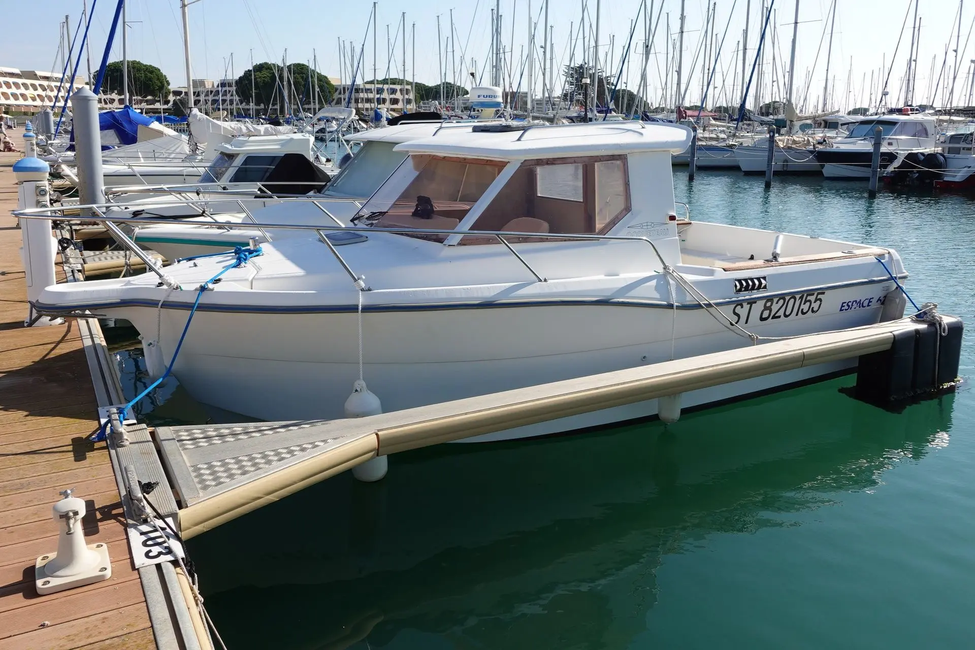 Ocqueteau Espace 625 — Bateau à moteur blanc amarré dans un port de plaisance, vu de trois quarts bâbord.