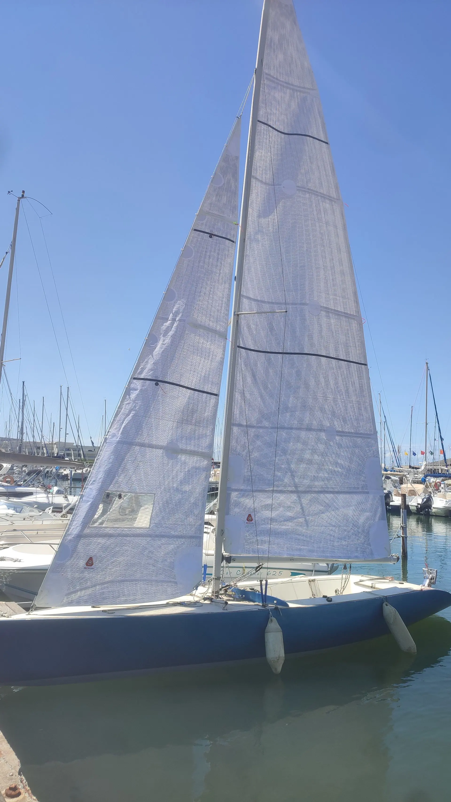 Monotype 750 — Voilier amarré, vu de côté, avec ses voiles hissées dans un port.