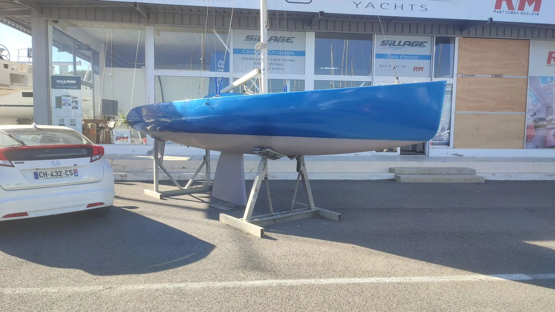 Monotype 750 — Voilier bleu présenté sur ber devant un chantier naval.