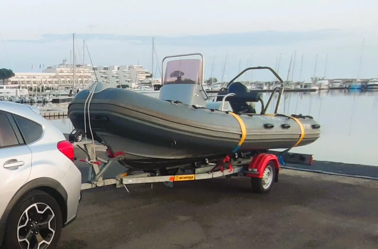 3D Tender XPRO 535 — Bateau pneumatique gris sur remorque, stationné dans un port de plaisance.