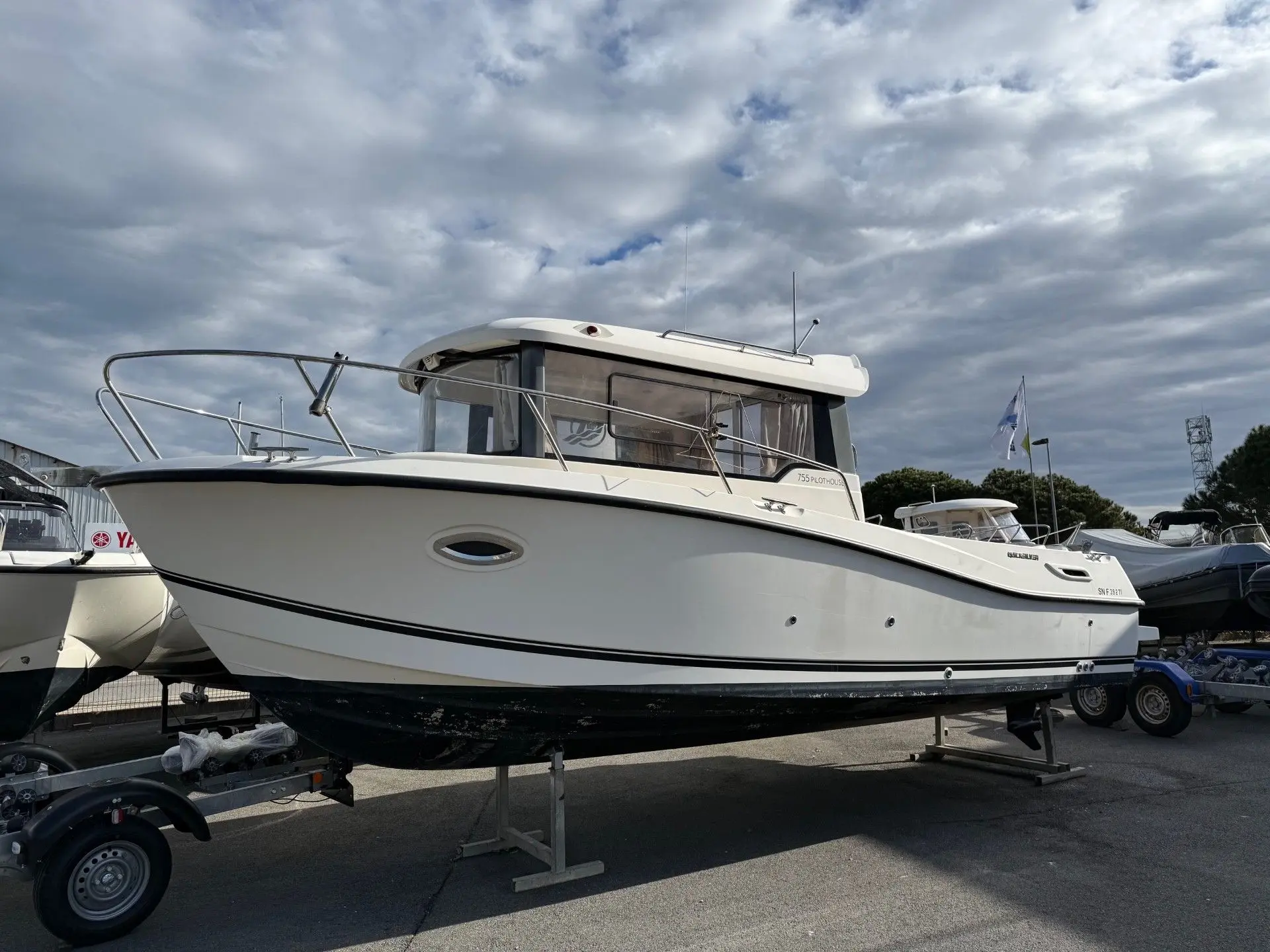 Quicksilver Captur 755 Pilothouse — Bateau blanc à cabine présenté sur sa remorque dans un parc nautique.