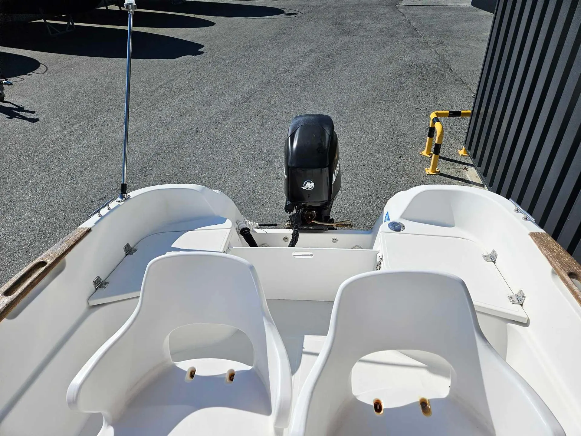 Quicksilver 525 Commander — Vue arrière du cockpit et du moteur hors-bord d’un bateau à moteur.