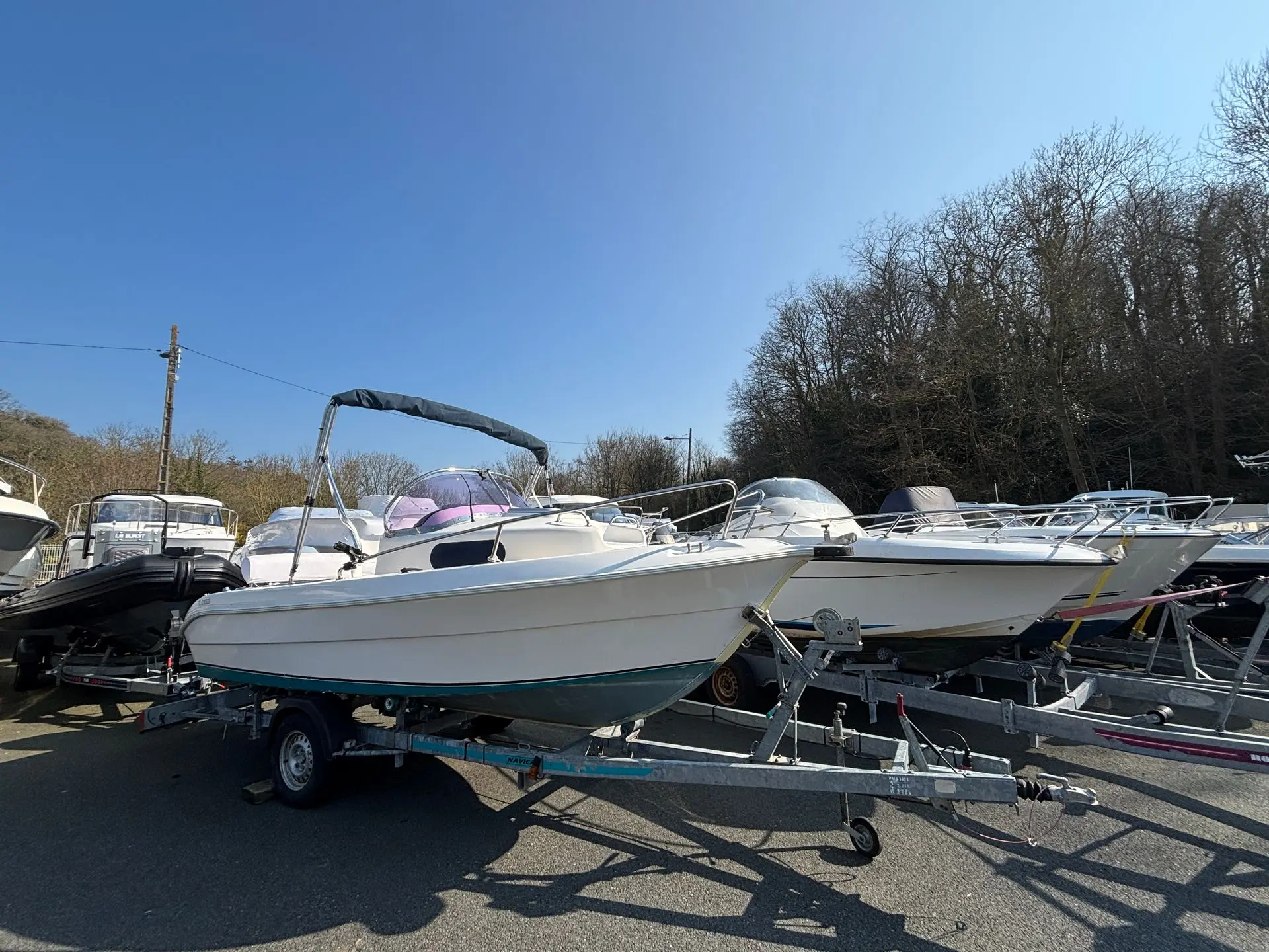 Janmor 531 Cabine — Bateau à moteur blanc avec taud, présenté sur sa remorque sur un parking.