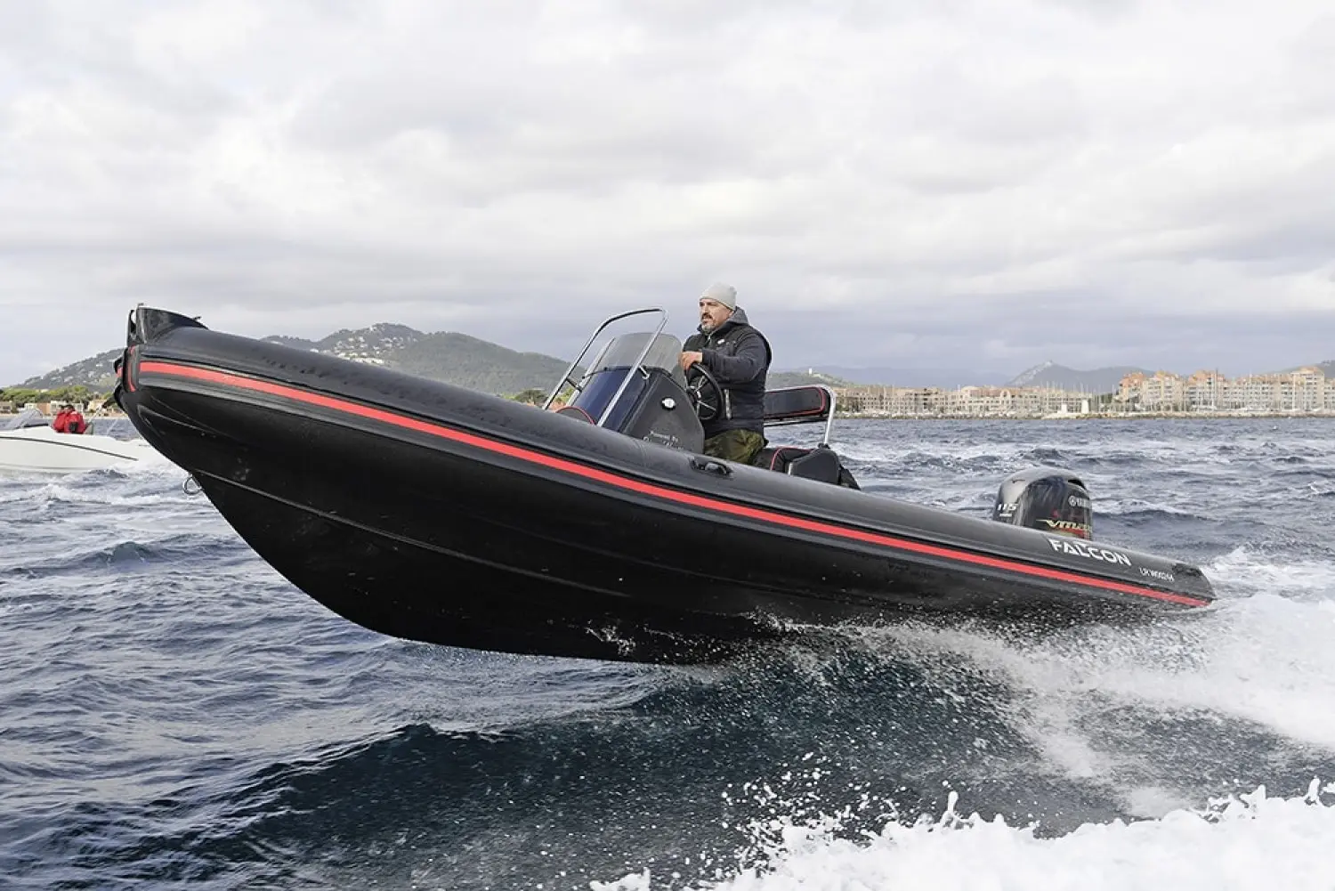 Falcon 575 — Bateau semi-rigide noir et rouge naviguant au large avec un pilote à la barre.
