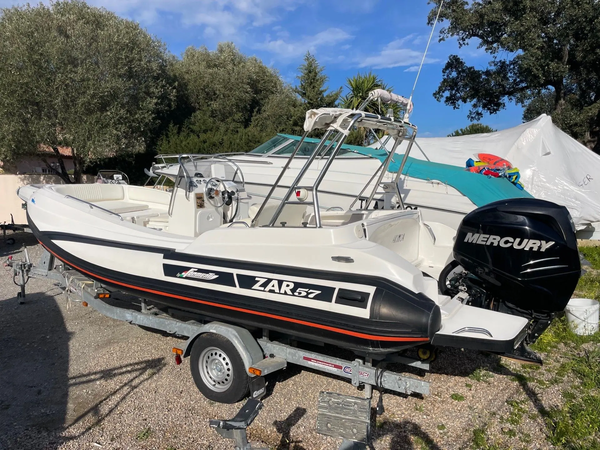 Zar Formenti Zar 57 Welldeck — Bateau pneumatique blanc à console, arceau et moteur hors-bord, sur remorque.