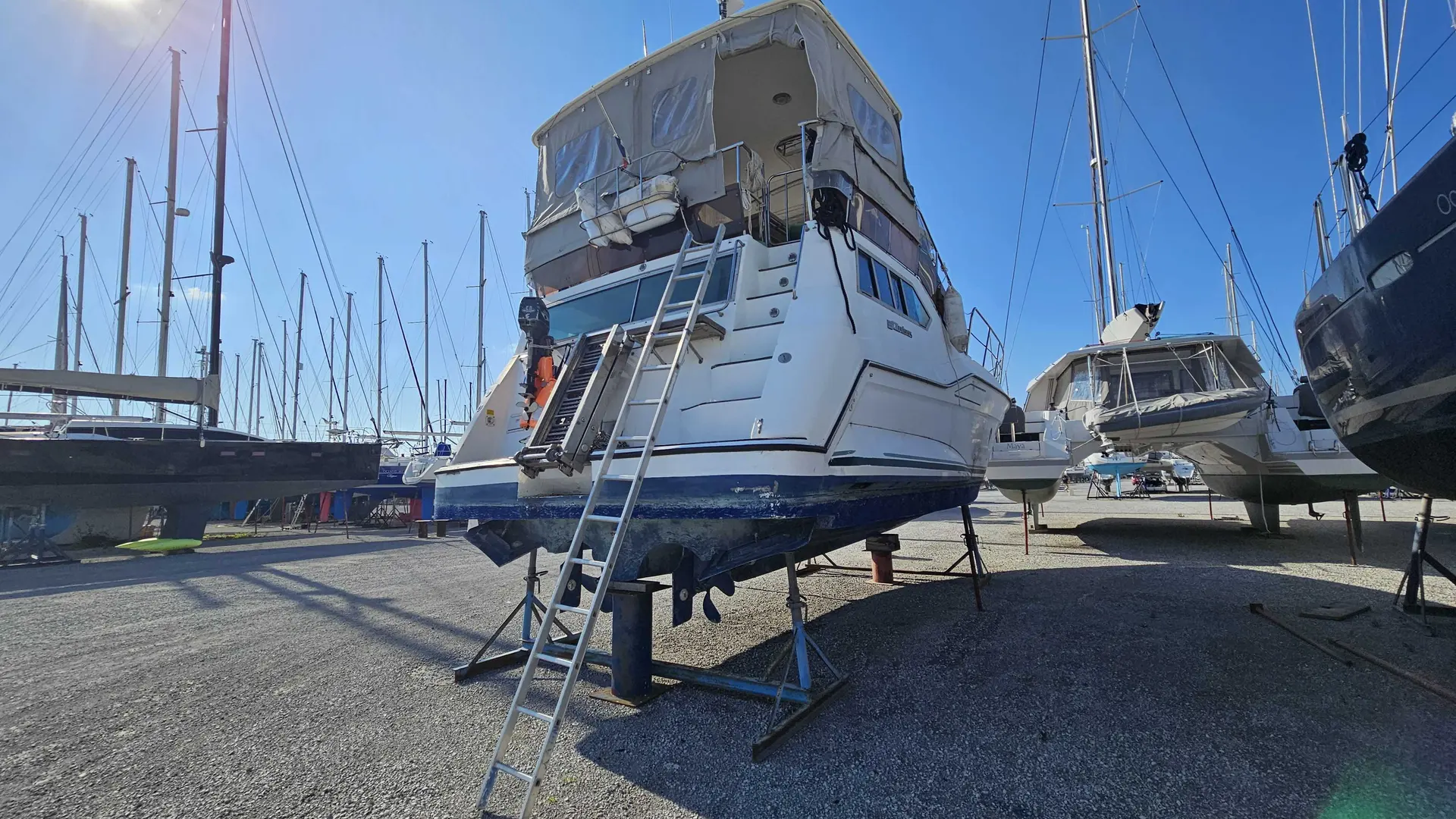 Cruisers Yachts 3850 AFT — Bateau à moteur blanc vu de l’arrière sur ber, dans un chantier nautique.