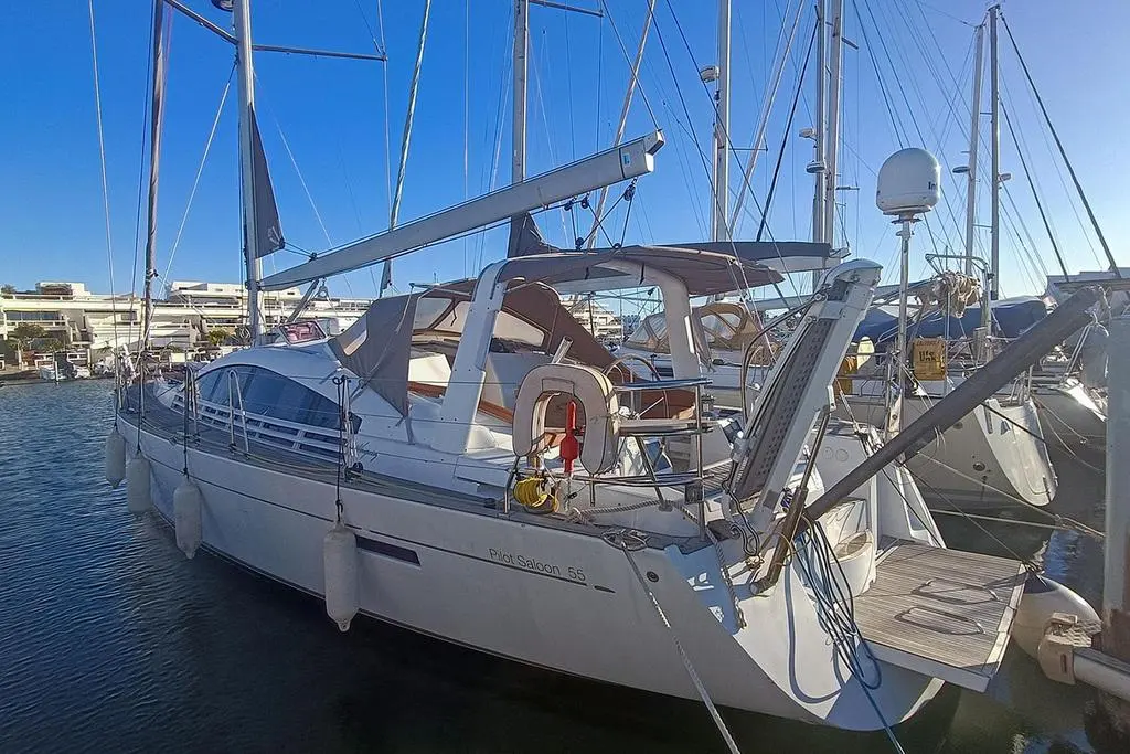 Wauquiez Pilot Saloon 55 — Voilier blanc amarré dans une marina, vu de trois quarts arrière.