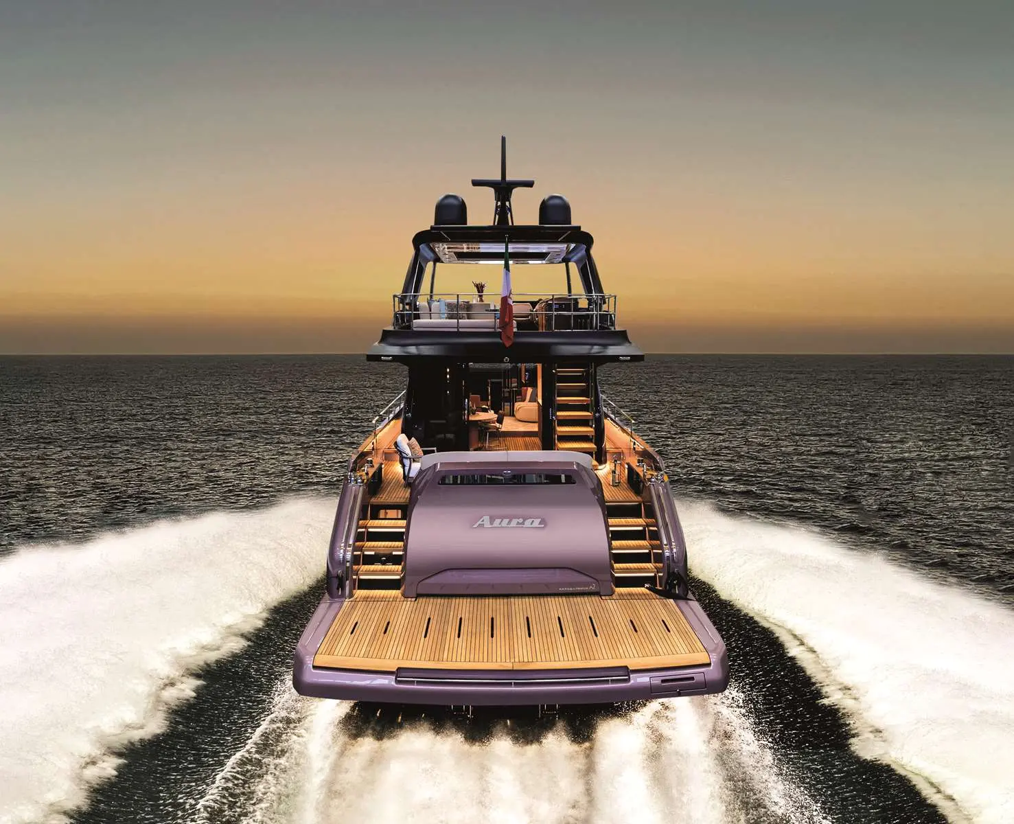 Cranchi Sessantadue  62 — Vue arrière d’un yacht naviguant en mer au coucher du soleil.