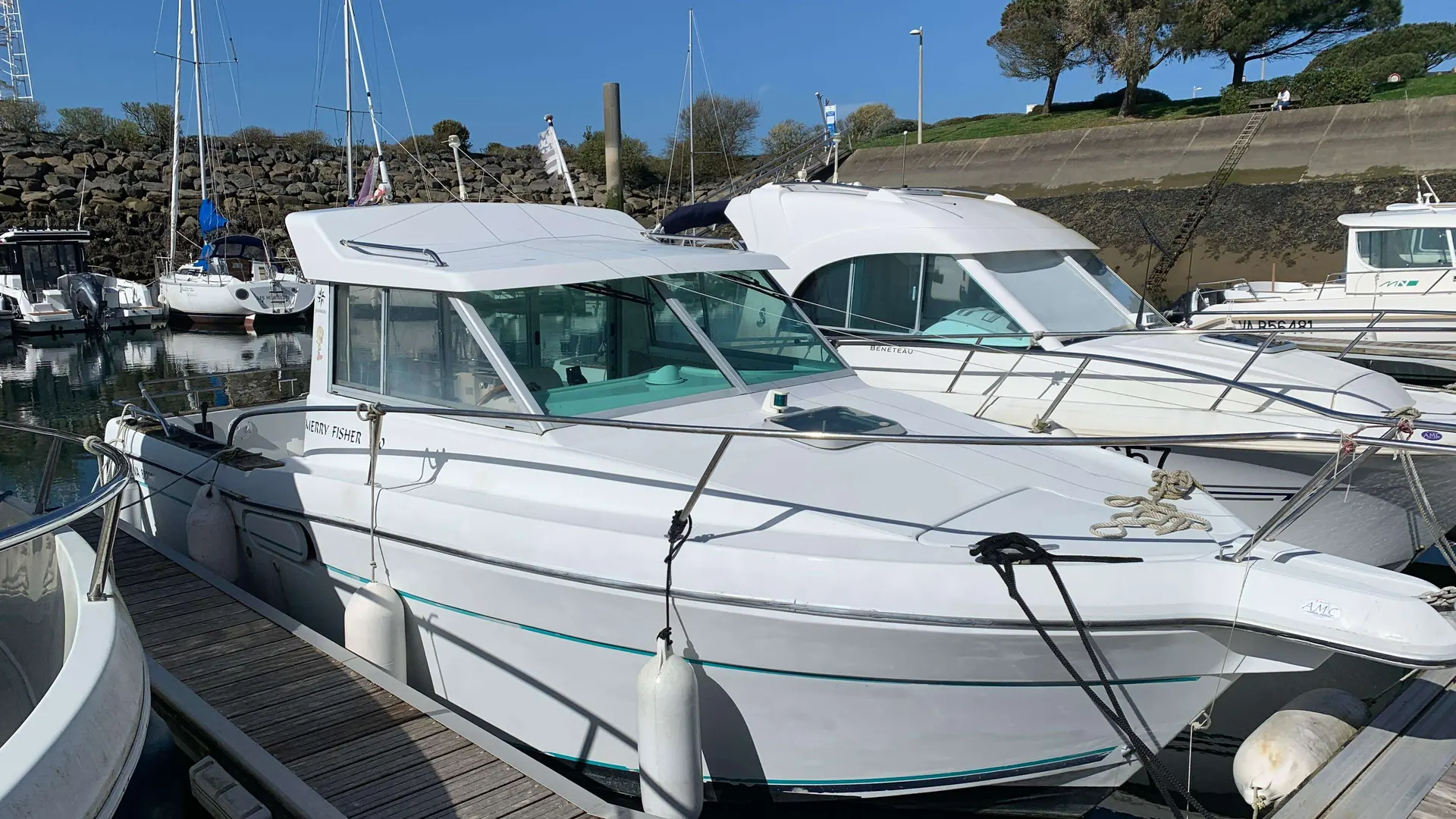 Jeanneau Merry Fisher 700 — Bateau à moteur blanc amarré dans un port, vu de trois quarts avant.